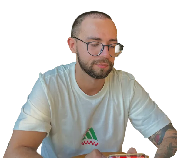 Guilherme Domingues, wearing glasses and a light T-shirt, looking down.